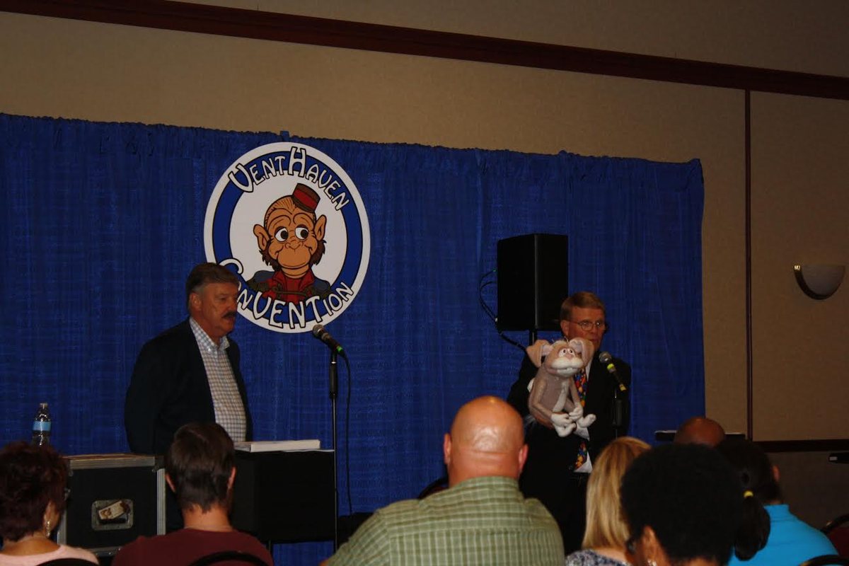 Mark Wade lecturing from the Vent Haven ConVENTion stage in 2017, holding a figure