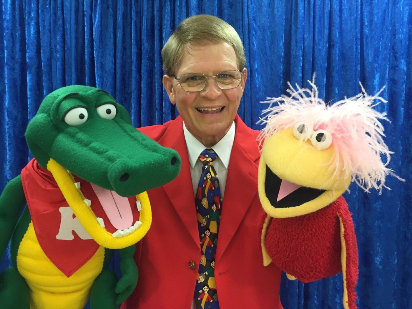 Mark Wade with a young audience member and three puppet characters