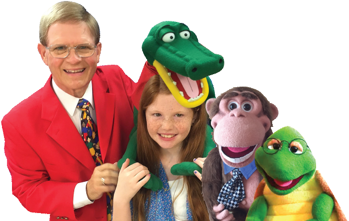 Mark Wade in a red jacket with a young volunteer, an alligator, a monkey and a turtle figure